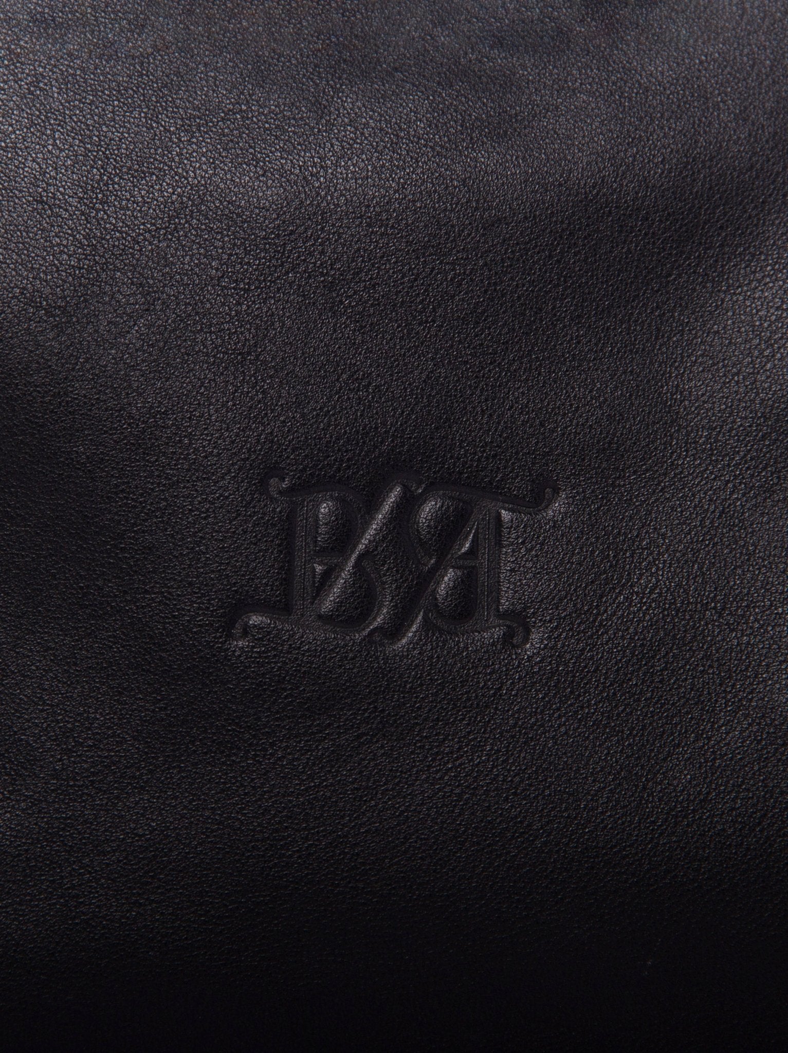 Detalle del logo timbrado Bess Madrid sobre piel de becerro negro